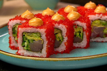 Delicious vibrant sushi rolls featuring fresh ingredients, including fish and vegetables, topped with creamy sauce and bright red fish roe in an appetizing arrangement.