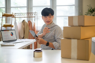 Young entrepreneur managing online orders and inventory in a home office. E-commerce concept.