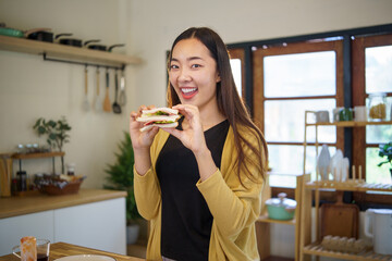Young woman enjoying a homemade sandwich during a relaxing day at home.