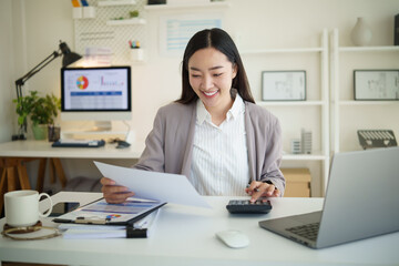 Confident female accountant checking documents with charts and graphs during work.