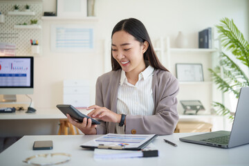 Female accountant reviewing income reports and using a calculator for data accuracy.