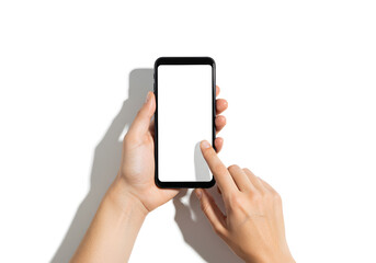 Top-down view of hands holding a smartphone with a blank white screen, while another hand points, ideal for showcasing apps or mobile content.