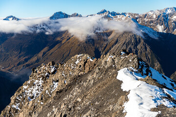 Happy adventurous hiker girl sits on summit of Avalanche Peak enjoying breathtaking views of snow covered mountains, Arthurs Pass National Park, Canterbury, South Island, New Zealand