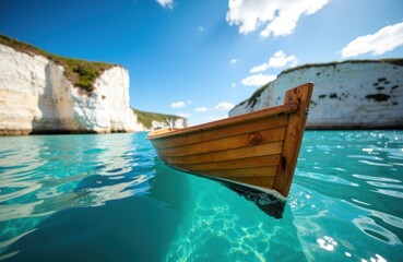 Obraz premium A wooden boat floats on clear blue water near white chalk cliffs under a bright sky