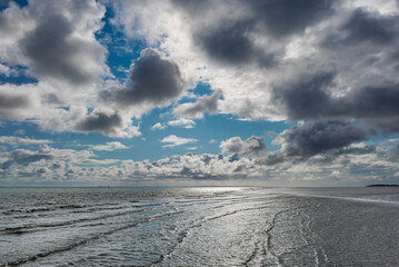 Dramatisch aufgebauschte Wolkenberge bei stürmischem Wetter über dem glitzernden Watt auf der...