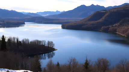landscape with a huge lake at the end of the autumn season. rocky mountains and high forests on the distant horizon. silhouettes of leafless trees reflected in the luster of the water