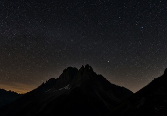 Starry night sky above mountain silhouette