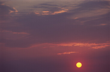 Pink clouds and yellow sun at sunset.