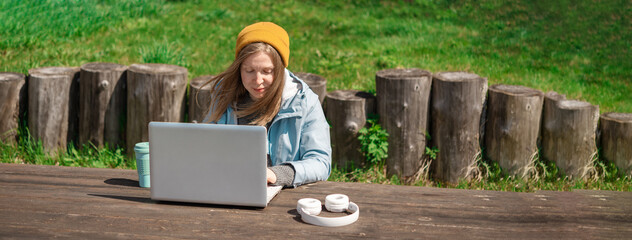 A girl is working on a laptop outdoors,banner