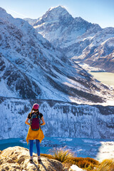 Brave hiker girl stands and admires turquoise Hooker Lake and Aoraki Mount Cook. Trail to Mueller Hut, Aoraki Mount Cook National Park, Canterbury, South Island, New Zealand