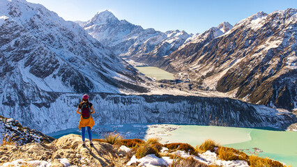 Brave hiker girl stands and admires turquoise Hooker Lake and Aoraki Mount Cook. Trail to Mueller Hut, Aoraki Mount Cook National Park, Canterbury, South Island, New Zealand