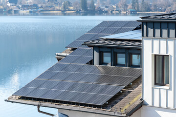 Alternative energy: solar panels on the roof of a country house by the lake.