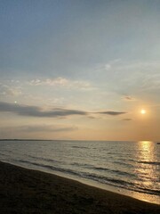 Obraz premium Tranquil Beach Sunset with Gentle Waves and Illuminated Clouds