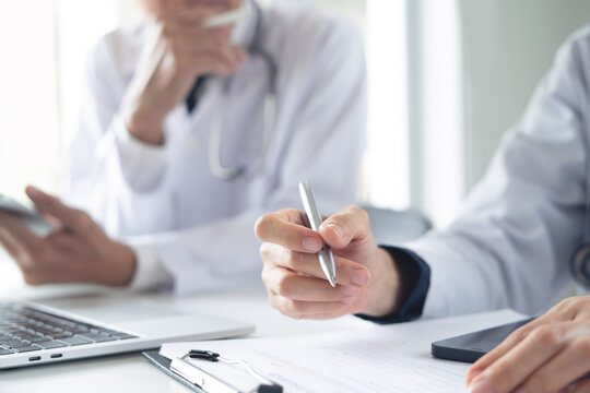 Two doctors discuss diagnosis, analyzing data on laptop in hospital office. Male and female medical professionals have a patient case conference, using laptop at doctor's office, close up