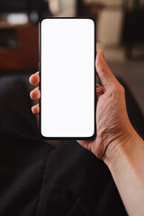 Man hold smartphone with white screen in his hand sitting on a couch in home environment