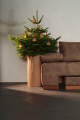 Small christmas tree with natural decorations indoor near couch