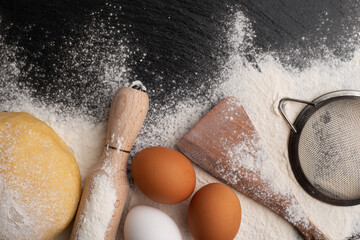 Baking utensils and dough laying on flour flat lay view with copyspace