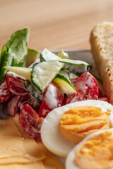 Close-up of a healthy breakfast plate with hard-boiled eggs, fresh cucumber and tomato salad with yogurt dressing, and golden toast slices.