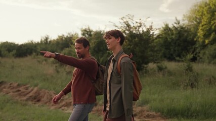 Dad and son walking through nature on hiking trail.