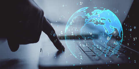 Finger touching laptop keyboard with glowing digital globe and binary code representing global network and futuristic cyberspace concept.