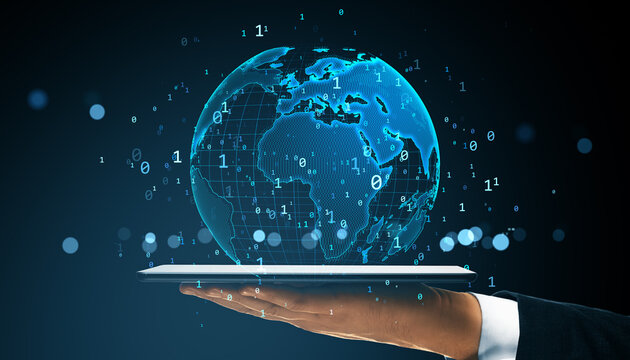 Digital holographic globe with binary code floating above a tablet held by a hand on dark background, symbolizing virtual global connectivity.