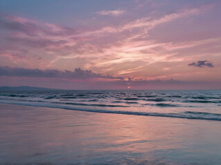 Pink purple sunset over ocean waves and sandy beach image