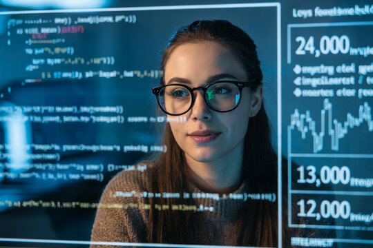 A professional headshot of a young woman data analyst in front of a digital display showing financial data.