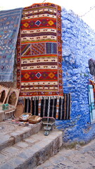 Colorful textiles hanging on a blue wall in the medina in Chefchaouen, Morocco