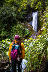 hiker brave girl stands next to and admires impressive powerful Ryde Falls up close. Best hidden gems/waterfalls near Oxford, Christchurch, canterbury, New Zealand, south island.