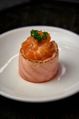 Artful Culinary Creation Featuring Delicately Wrapped Salmon on Elegant Plate with Tomato Garnish and Fresh Green Herb Accent