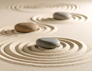 Three smooth grey and brown stones rest in a meticulously raked zen garden, with concentric circular patterns radiating from each stone in the fine, light-colored sand, creating a serene and balanced 