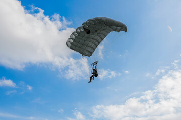 Skydiver in Action,  A skydiver gliding through the blue sky with a fully deployed parachute, showcasing the thrill and freedom of airborne adventure.