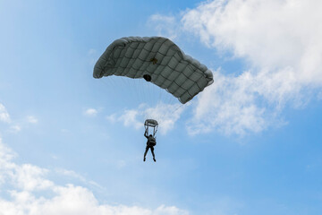 Skydiver in Action,  A skydiver gliding through the blue sky with a fully deployed parachute, showcasing the thrill and freedom of airborne adventure.