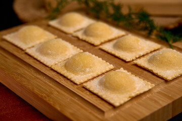 Delicate, Homemade Ravioli Ready for Cooking, Showcasing the Art of Italian Cuisine with Its Perfectly Shaped Dough and Fillings, Placed on a Wooden Board.