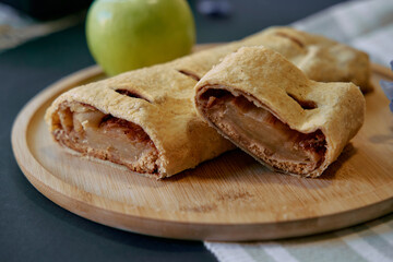 Deliciously Baked Apple Strudel Filled with Sweet Cinnamon Apples Showcased on a Wooden Serving Board with a Fresh Green Apple for Contrast