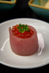A Delicate Sushi Creation Featuring Fresh Tuna and Vibrant Salmon Roe Served on a Simple White Plate with a Touch of Green Garnish