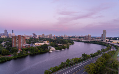Boston skyline at dusk with river and highway.