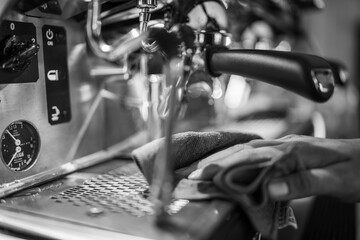 Close up of a barista cleaning an espresso machine portafilter with a cloth while hot water runs through it creating steam and bubbles