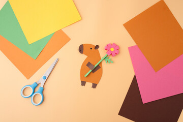 Flat lay paper capybara craft scene with flower, scissors, and glue for toy brands, educational...