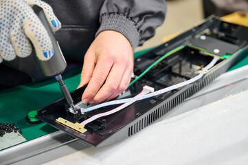 Repair technician assembles electronic device in workshop during daytime with focus on precision...