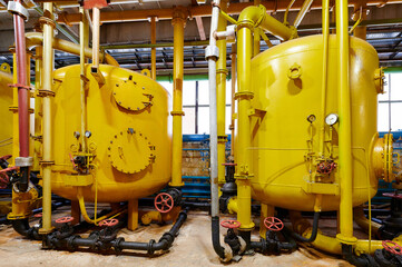Large yellow industrial tanks and pipes within a manufacturing facility showcasing machinery and...
