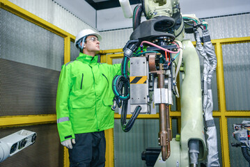 Robotic machine enginee is checking the operation of the robot arm manufacturing machine,machinery welding robots in production at factory industry.