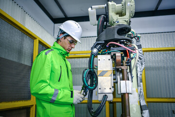 Robotic machine enginee is checking the operation of the robot arm manufacturing machine,machinery welding robots in production at factory industry.