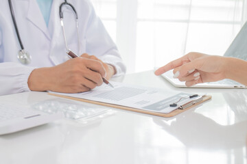 A uniformed doctor consults with a teenage patient in a hospital office, explaining the diagnosis,...