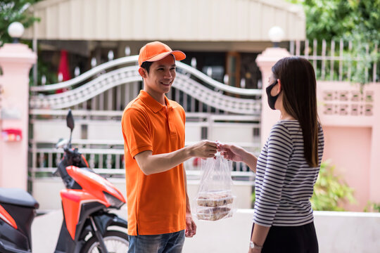 Smiling Asian courier deliveryman deliver sweet bakery to woman at home