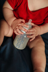 Little baby boy holding bottle with milk, healthy baby food concept, cozy lifestyle