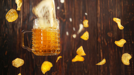 glass of foamy golden cold beer falls down with crisps flakes.