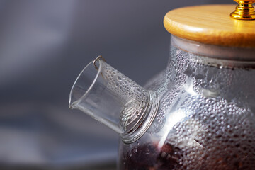 A detailed close up view of a beautiful glass teapot featuring a wooden lid