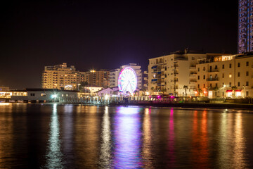 Obraz premium Ruota panoramica di notte in citta sul mare