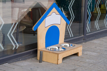A wooden feeding trough with bowls for dogs at a café or shop.